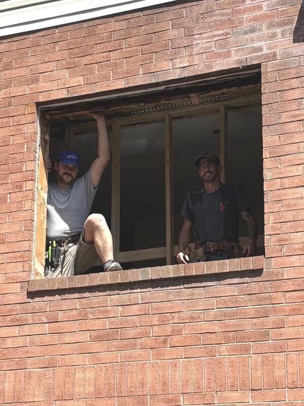 Deux membres de l'équipe dans l'ouverture d'un mur de brique